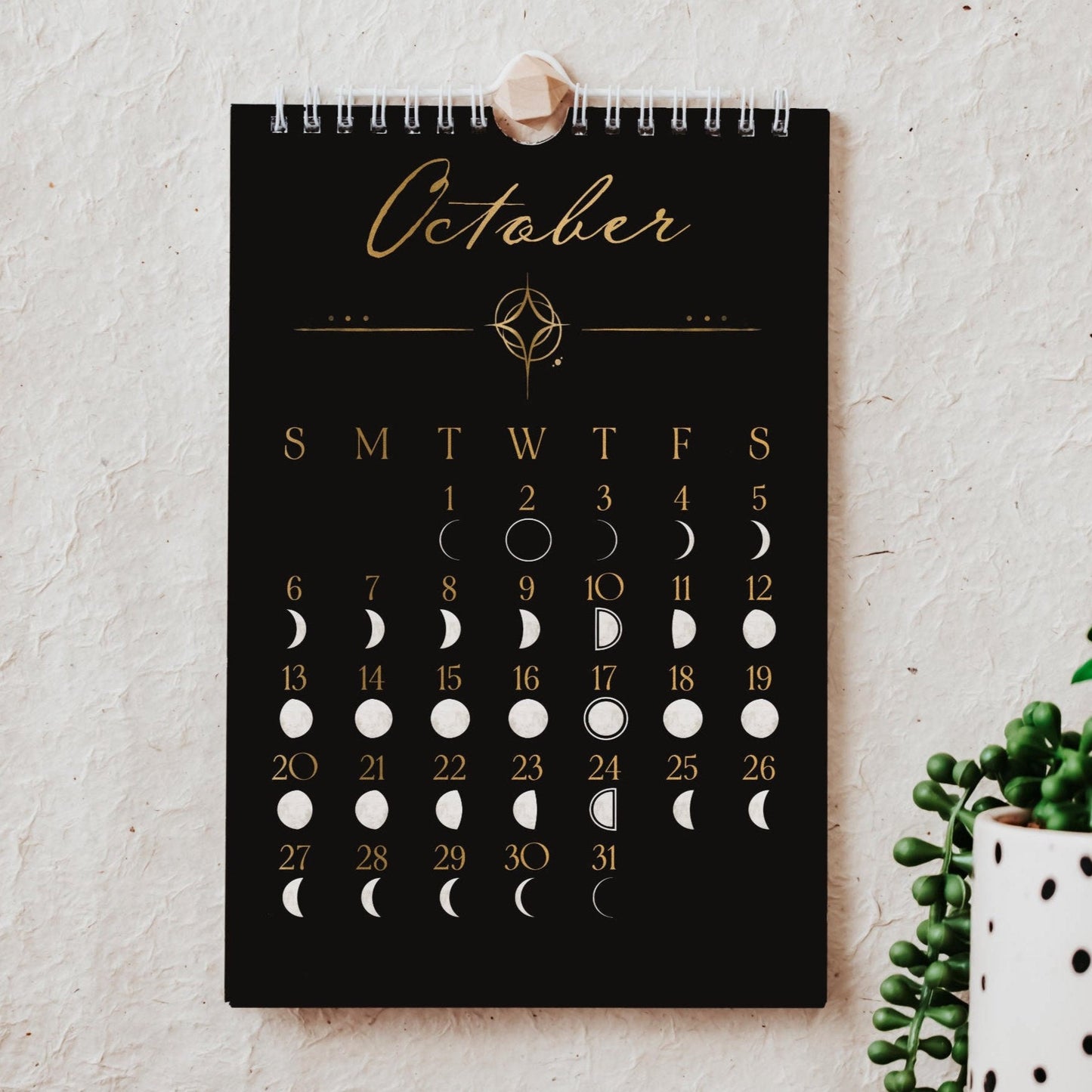 a small black and gold 2024 calendar that showcases the phases of the moon each day of the year